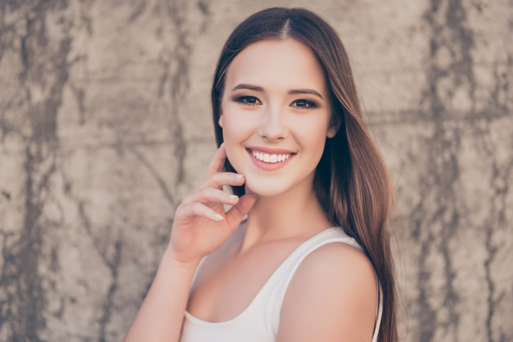 Young woman with long brown hair showing a bright, even smile, illustrating the discreet look of Invisalign clear aligners offered by Dr. Ryan Hecht at Montana Smiles Orthodontics in Billings, Montana.
