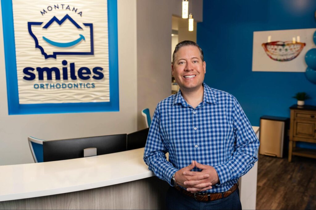Smiling orthodontist at Montana Smiles Orthodontics office in Billings, featuring logo and welcoming environment.