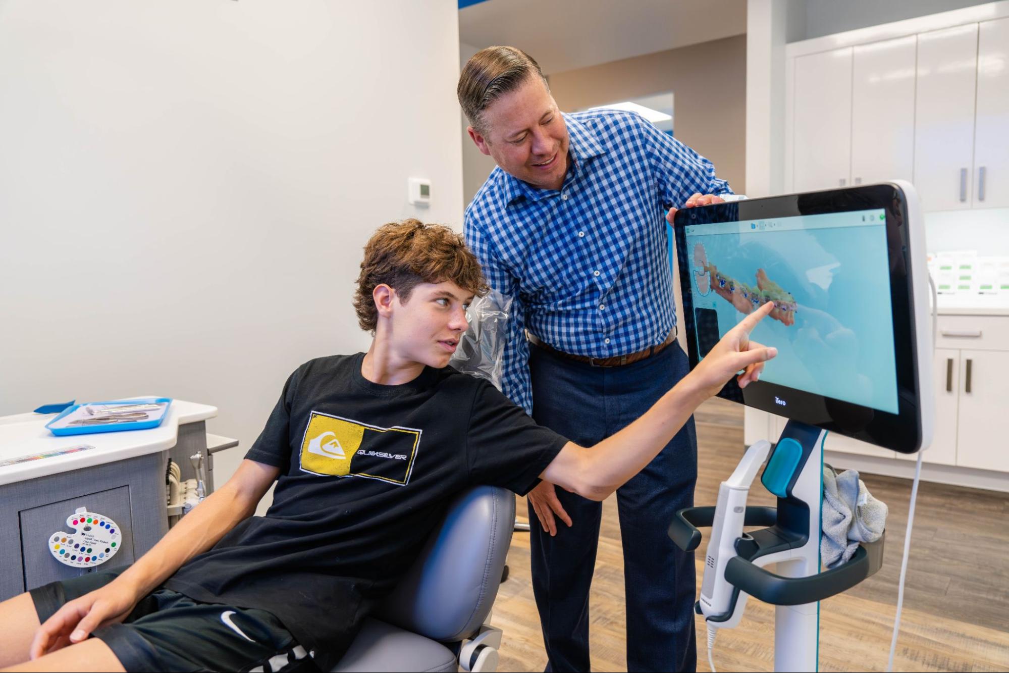 Young patient discussing braces treatment with orthodontist at Montana Smiles Orthodontics, showcasing digital orthodontic tools in a modern clinic setting.